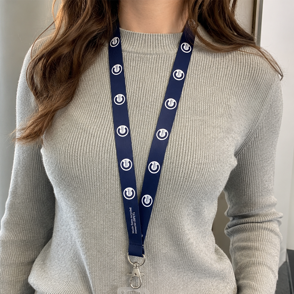 Person wearing a gray sweater with a blue lanyard featuring the cranfield university logo.