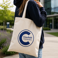 Person holding a tote bag with Cranfield University logo outdoors.