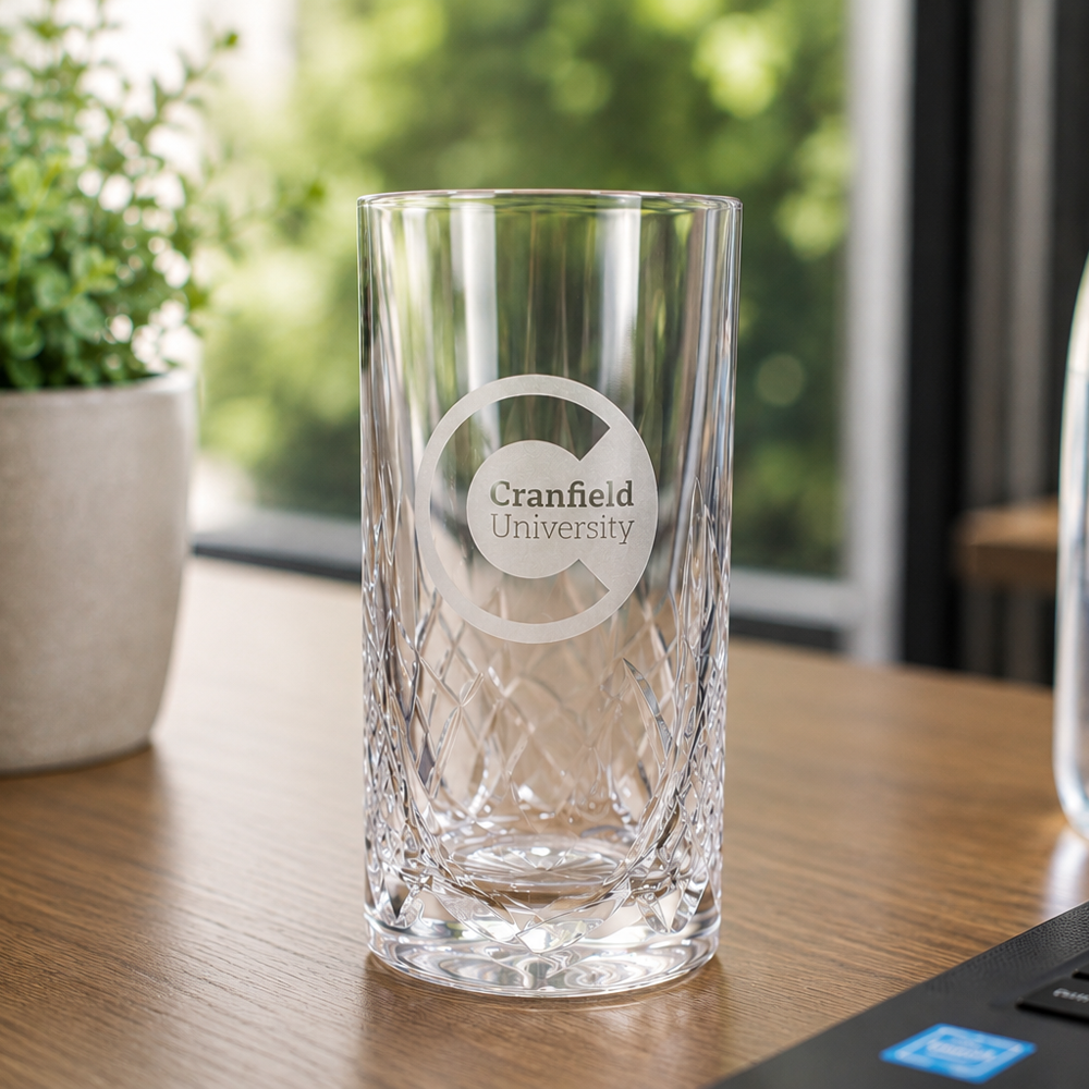 Clear glass with 'Cranfield University' engraving on a wooden table.